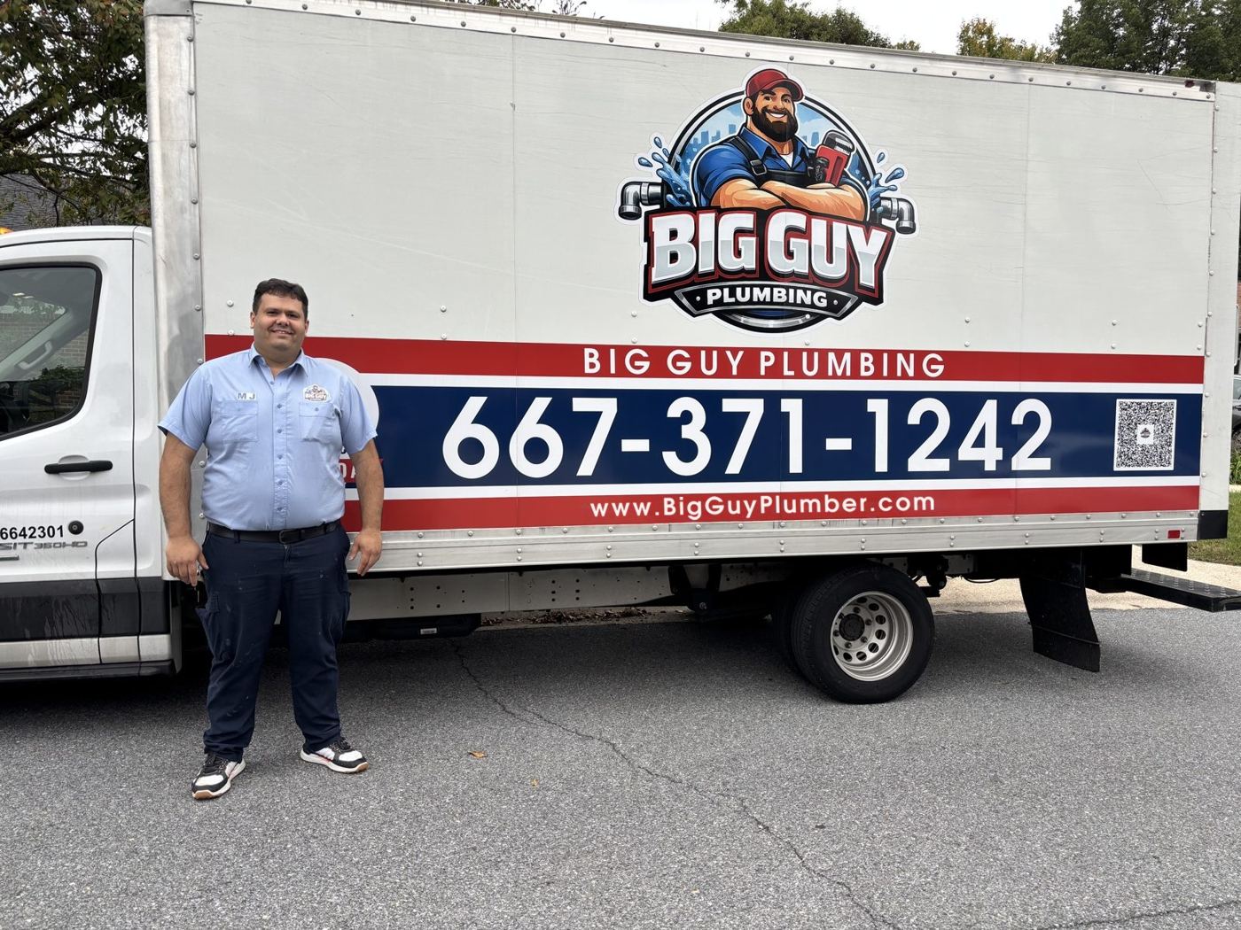 MJ, owner of Big Guy Plumbing, standing beside his branded work truck